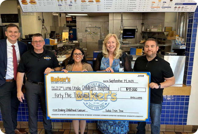 three men and 2 woman stand in front of an oversized cheque from bakers drive thru to Loma Linda children's hospital for $45,000