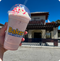 A person holding a bakers drive thru milkshake in front of a bakers drive thru store